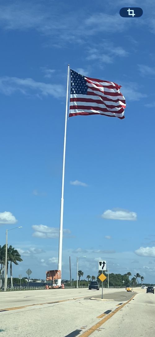 Cape Coral's 250-foot flagpole flying its flag under blue skies at Bernice Braden Park, photographed September 17, 2026